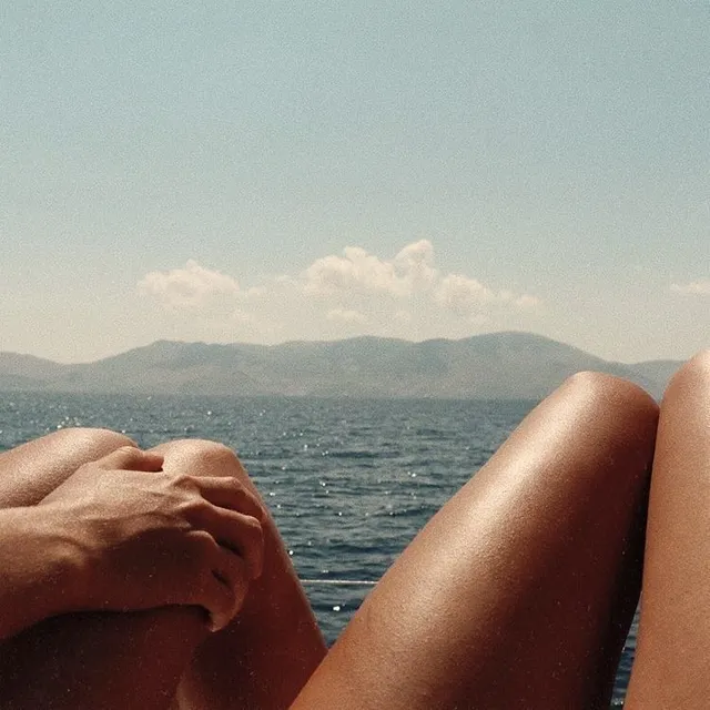 Legs stretched out on a boat deck, open water and mountains ahead