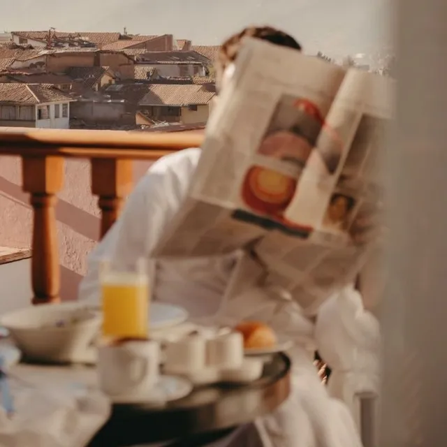 Breakfast and the morning paper on a hotel balcony above terracotta rooftops